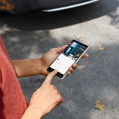  A man holding a Google Pixel 2 in his left hand, with the index finger of his right hand pressing on the screen to activate Google Assistant  